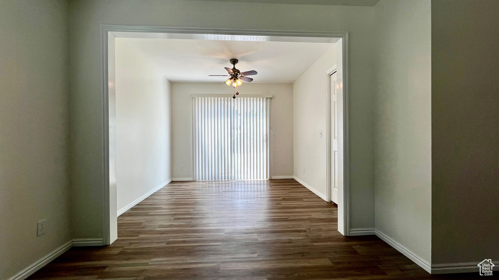 Unfurnished room featuring dark wood-style floors, baseboards, and a ceiling fan
