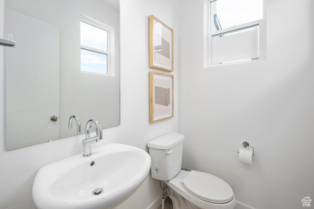 Bathroom featuring a sink, toilet, and baseboards