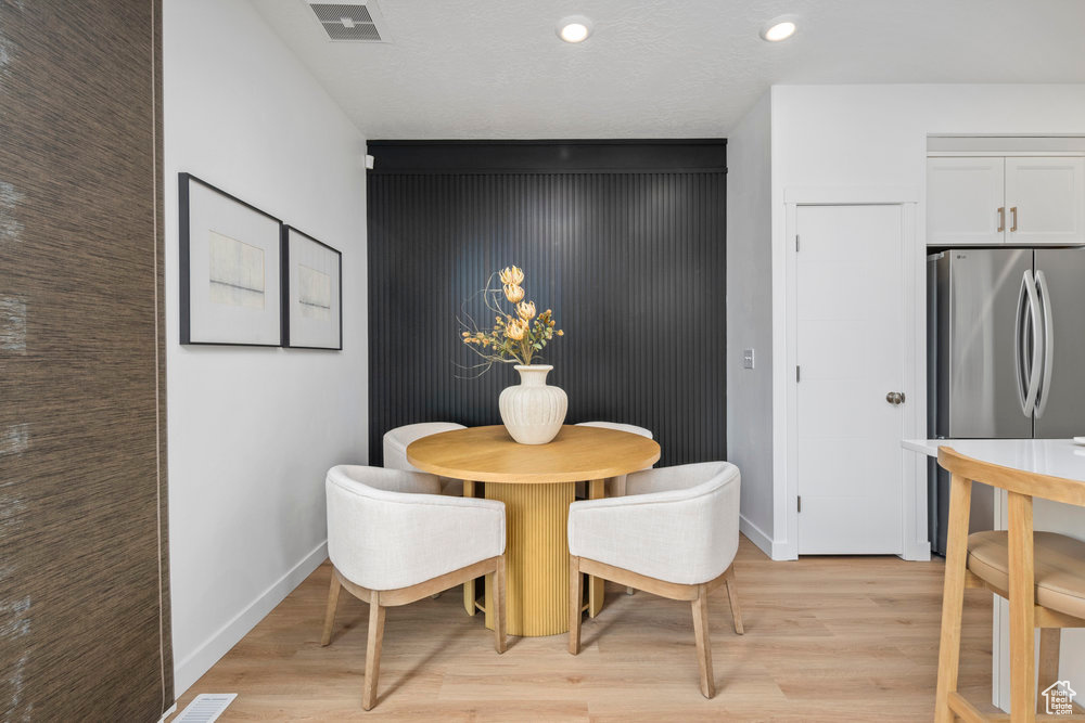 Dining area with light wood-style floors, baseboards, recessed lighting, and an accent wall