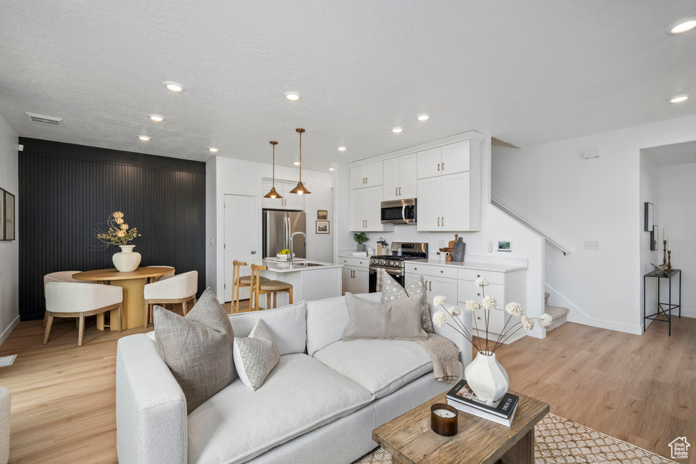 Living area featuring stairs, light wood finished floors, recessed lighting, and baseboards