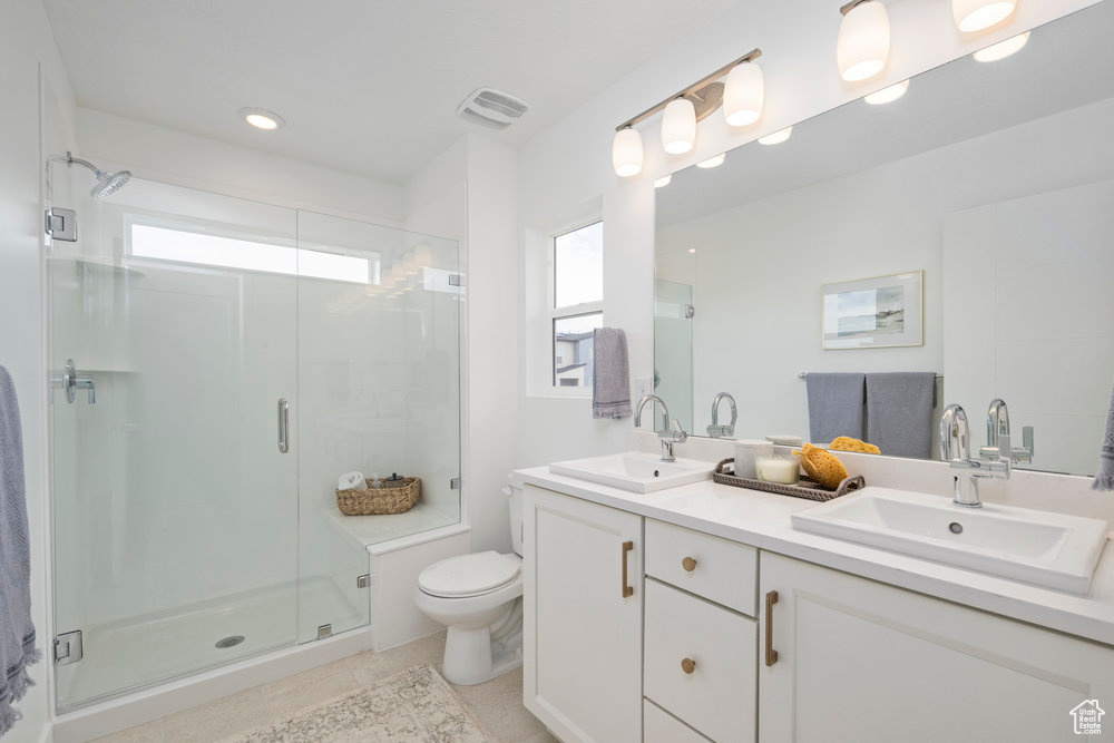 Full bath featuring double vanity, a stall shower, toilet, tile patterned floors, and recessed lighting