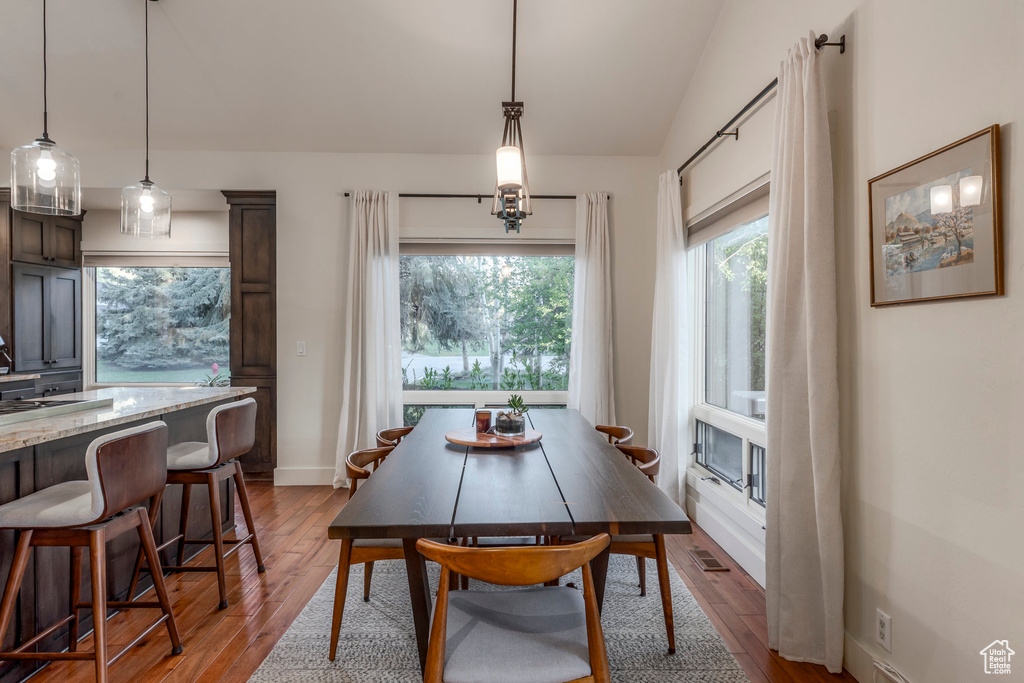 Dining room featuring wood finished floors, vaulted ceiling, and baseboards