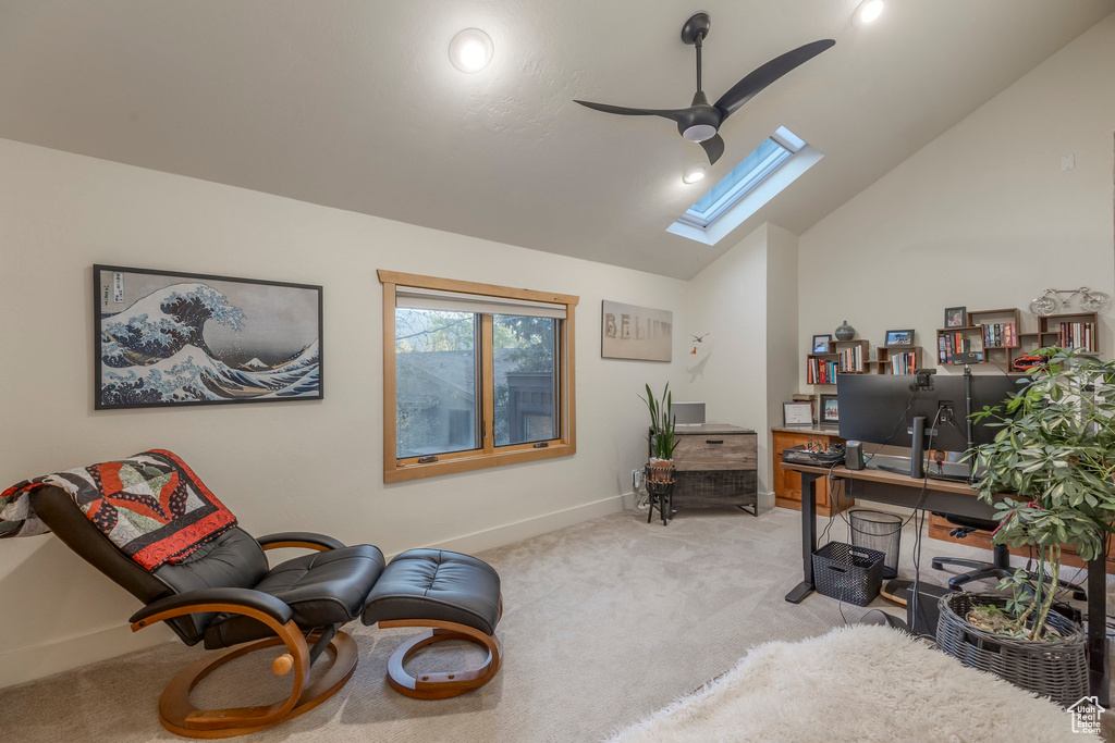 Office area with light colored carpet, a ceiling fan, a skylight, lofted ceiling, and baseboards