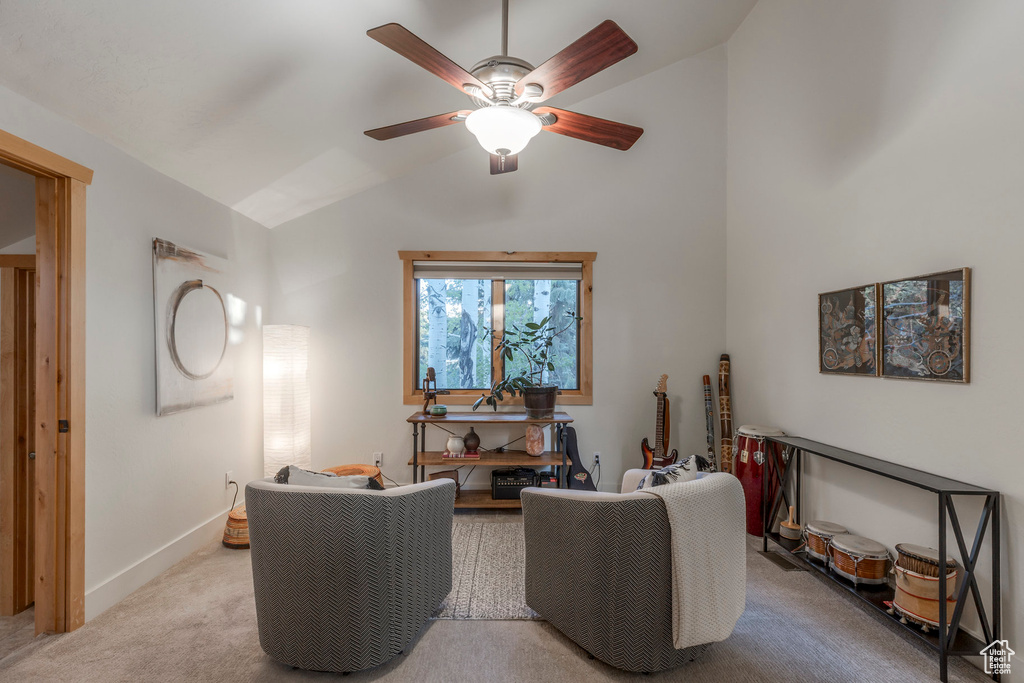 Carpeted living area with vaulted ceiling, ceiling fan, and baseboards