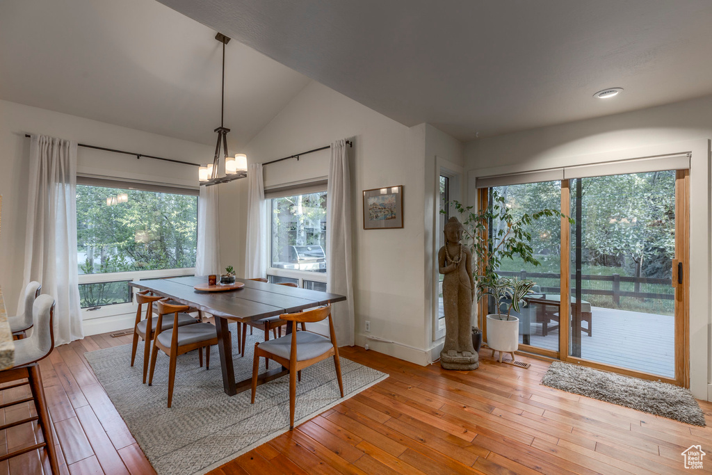 Dining area with light wood-style floors, vaulted ceiling, baseboards, a chandelier, and recessed lighting