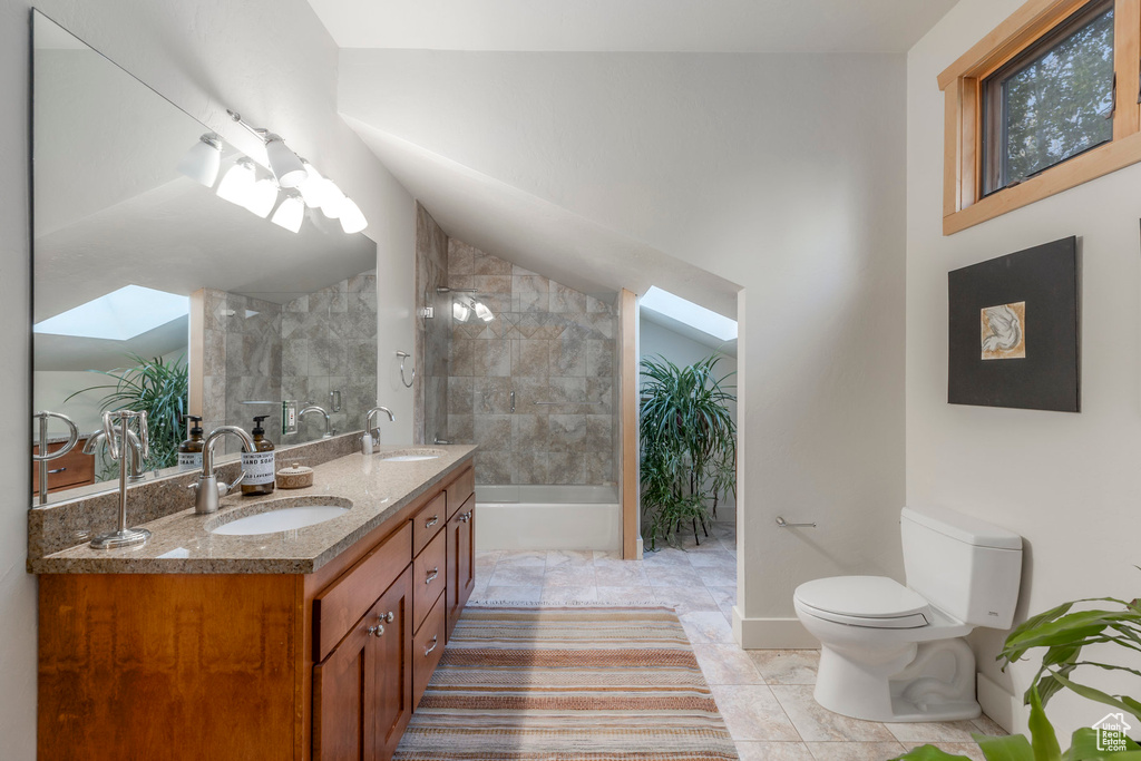 Full bathroom featuring toilet, double vanity, a skylight, shower / bath combination, and lofted ceiling