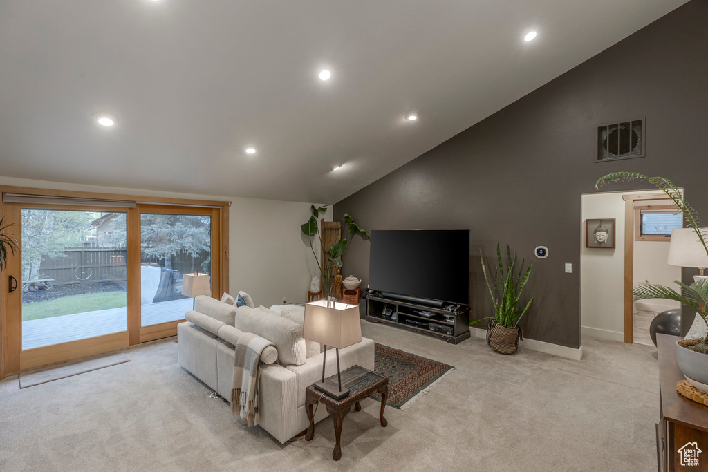 Living area featuring recessed lighting, light colored carpet, baseboards, and high vaulted ceiling