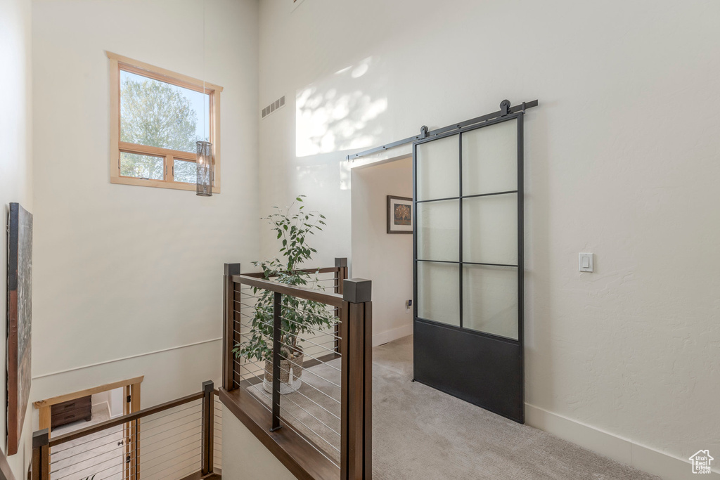 Hallway with carpet, an upstairs landing, a barn door, and baseboards
