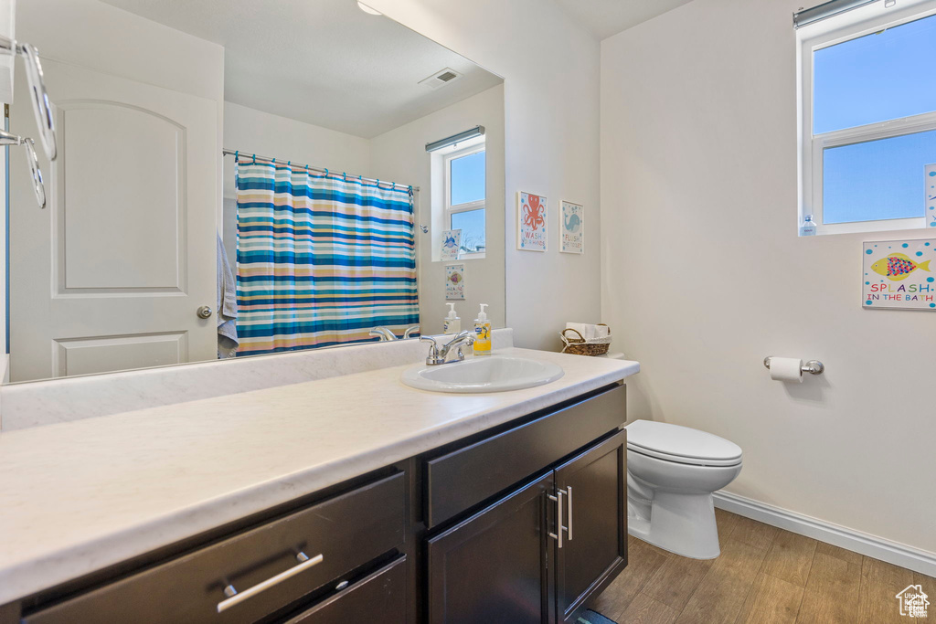 Bathroom featuring baseboards, toilet, vanity, wood finished floors, and curtained shower