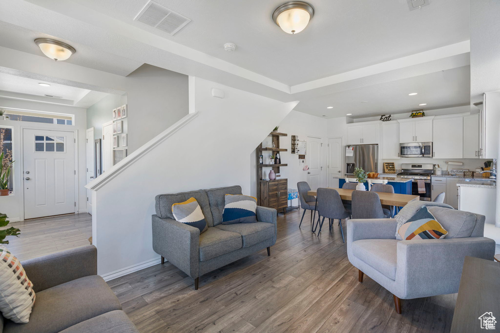 Living room featuring wood finished floors, baseboards, recessed lighting, and stairs