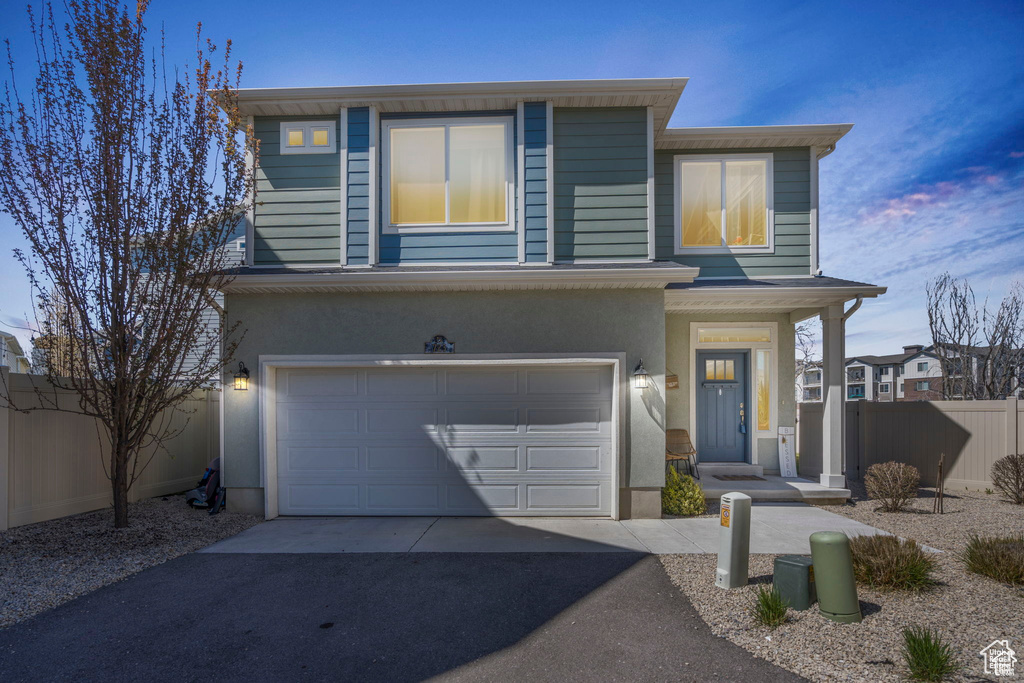 View of front facade with asphalt driveway, a garage, and stucco siding