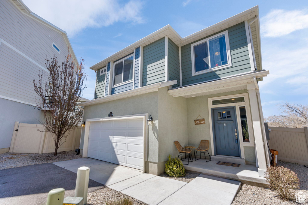 View of front of property featuring covered porch, stucco siding, an attached garage, and driveway