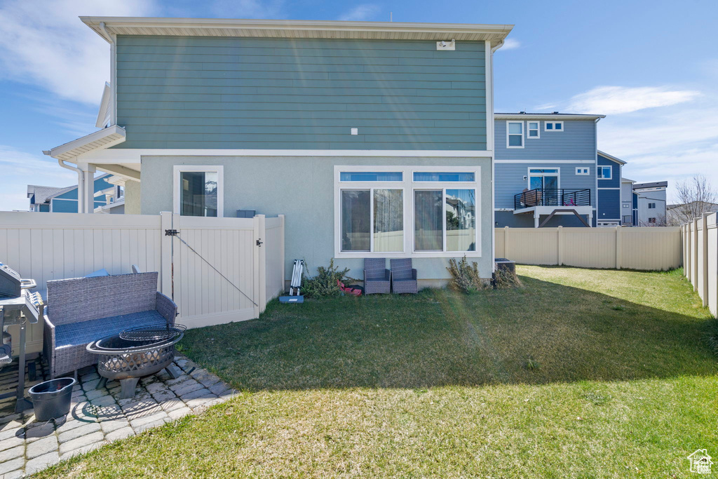 Back of house with a gate, an outdoor fire pit, stucco siding, and a patio