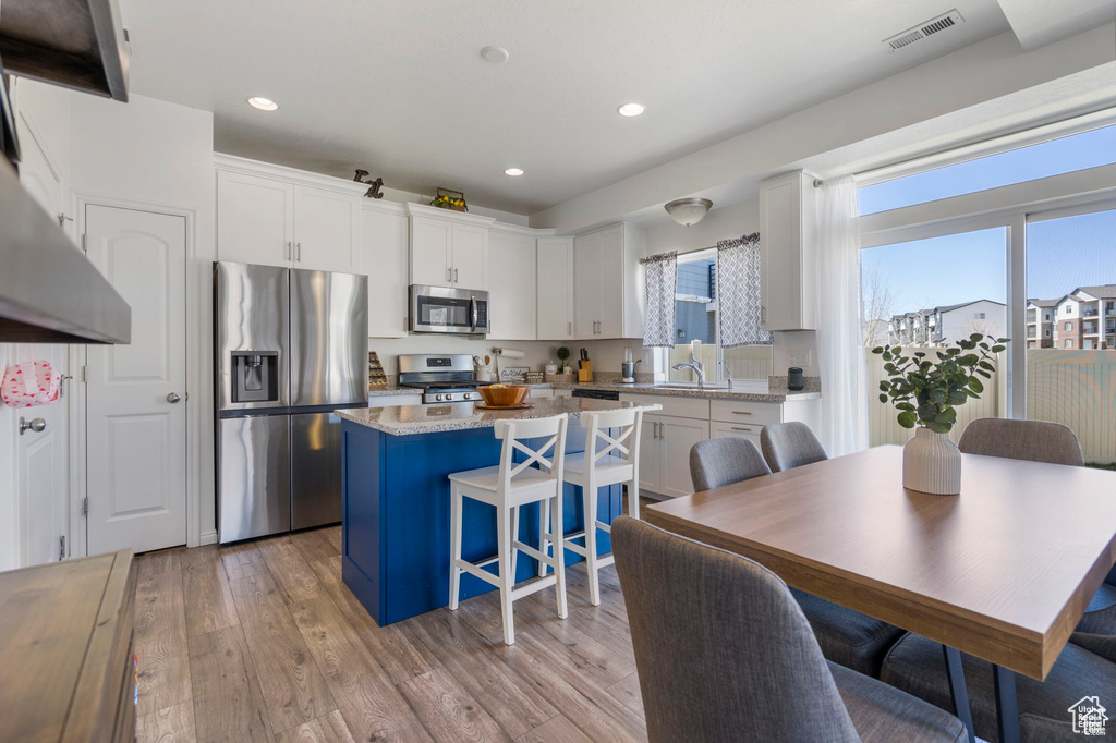 Kitchen with stainless steel appliances, healthy amount of natural light, a center island, white cabinetry, and recessed lighting