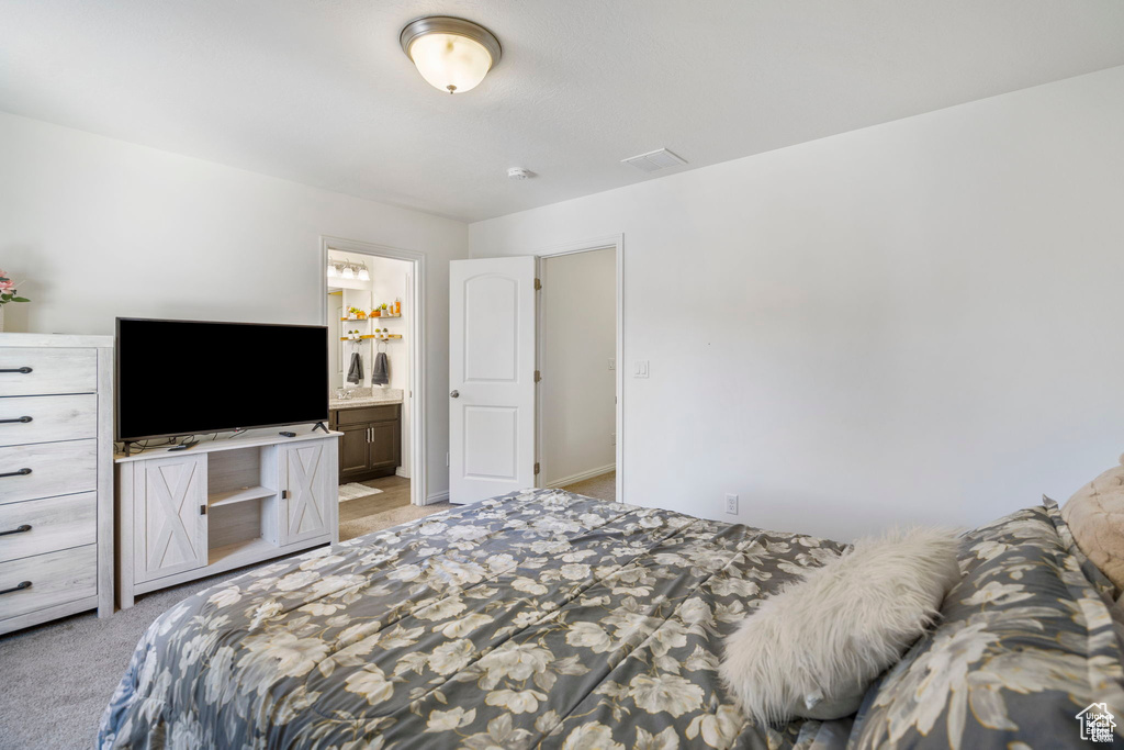 Bedroom with light carpet and ensuite bathroom