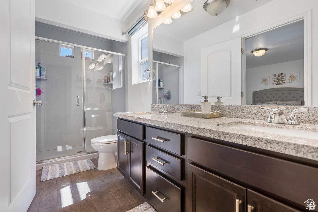 Full bathroom with wood finished floors, toilet, double vanity, and a shower stall