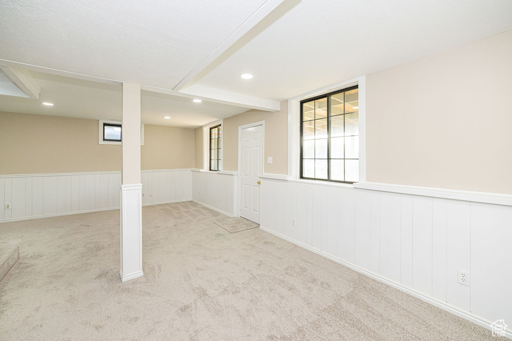 Basement featuring plenty of natural light, carpet, wainscoting, and recessed lighting