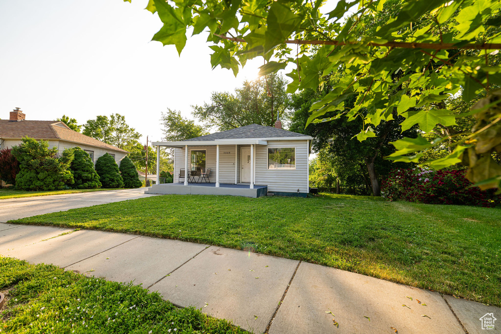 View of front facade featuring covered porch, a front lawn, and driveway