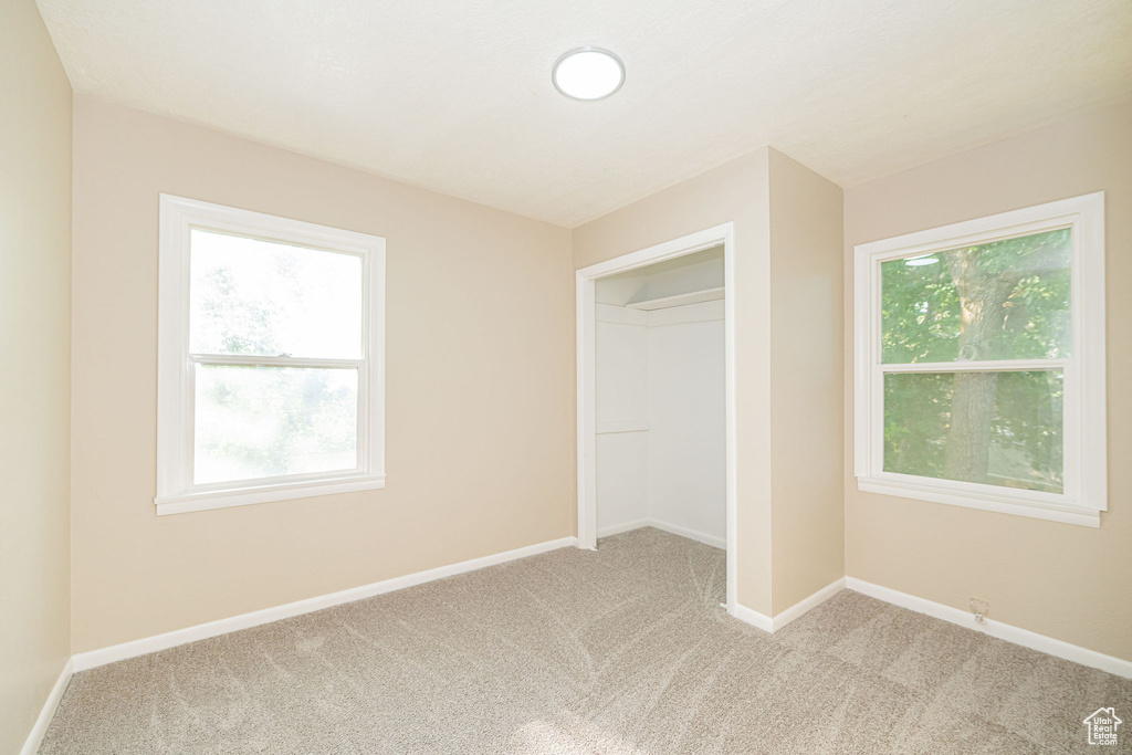 Unfurnished bedroom with light colored carpet and baseboards