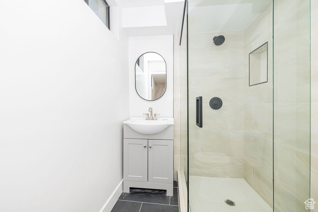 Full bathroom with vanity, a stall shower, tile patterned floors, and baseboards
