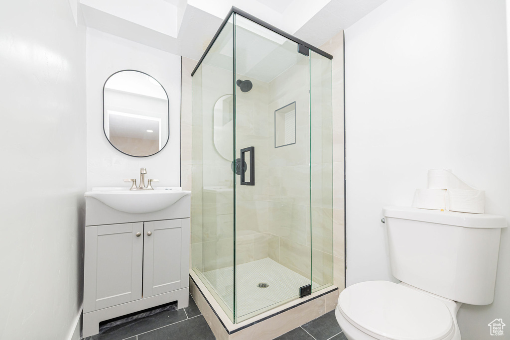 Full bathroom featuring toilet, tile patterned flooring, vanity, and a shower stall