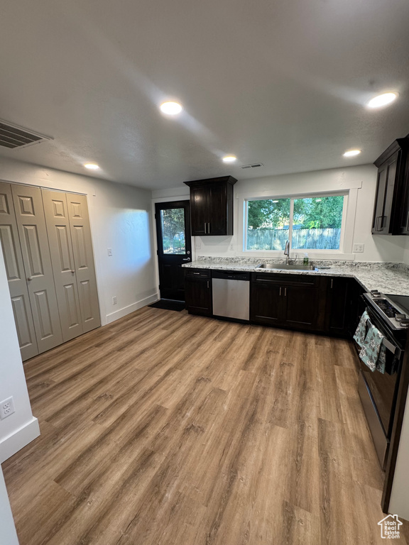 Kitchen with stainless steel dishwasher, black range oven, a sink, light wood-type flooring, and recessed lighting