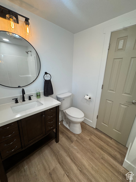 Full bath with wood finished floors, vanity, toilet, a shower, and a textured ceiling