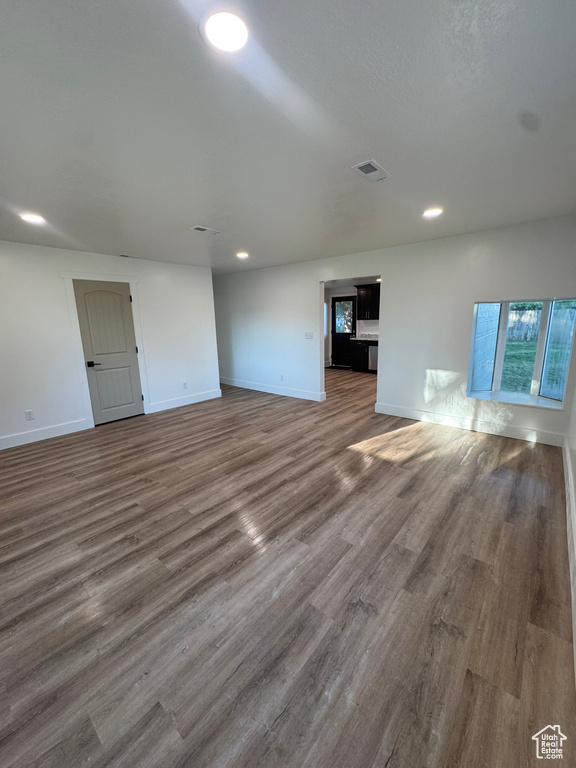 Unfurnished living room with wood finished floors, baseboards, and recessed lighting