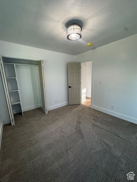 Unfurnished bedroom featuring carpet flooring, a textured ceiling, baseboards, and a closet
