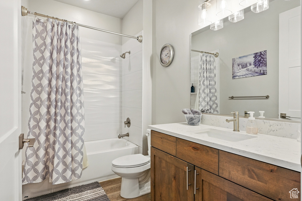 Full bathroom with shower / tub combo, vanity, wood finished floors, and toilet