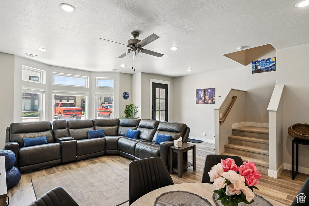 Living room featuring recessed lighting, light wood-style floors, baseboards, a ceiling fan, and stairs