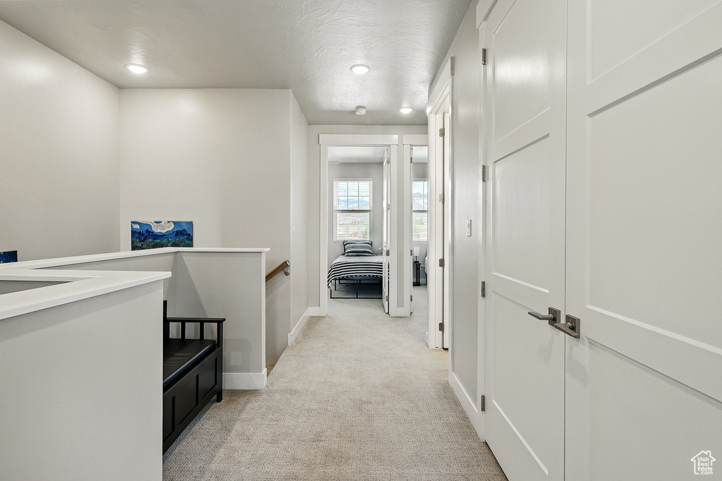 Corridor featuring an upstairs landing, light carpet, baseboards, and recessed lighting