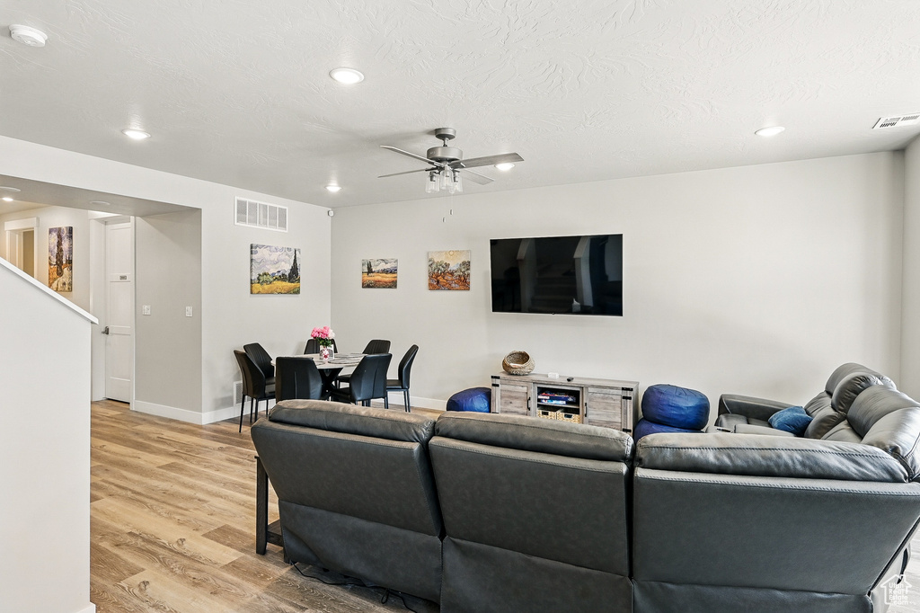 Living room featuring light wood-style flooring, recessed lighting, ceiling fan, baseboards, and stairs