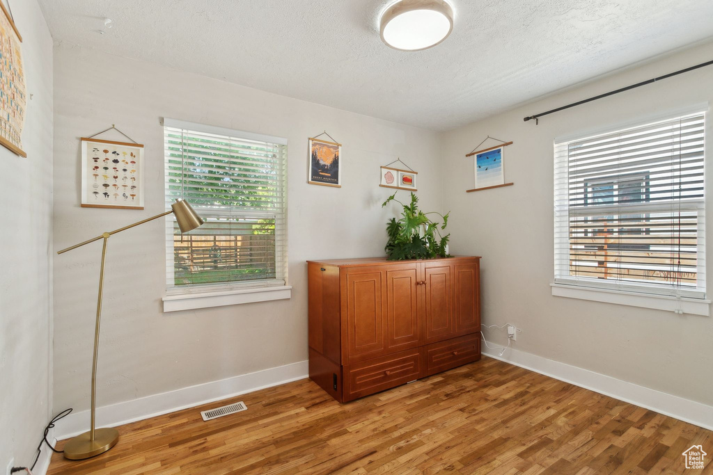 Office space with light wood-style floors, baseboards, and a textured ceiling