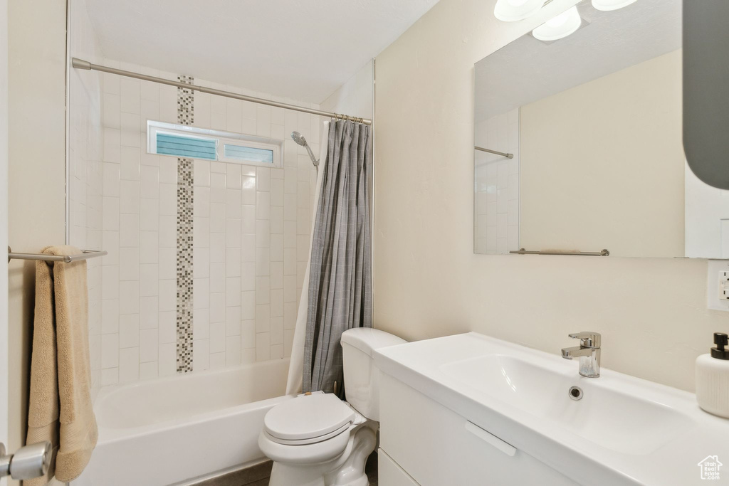 Full bathroom with vanity, shower / bath combo, and toilet