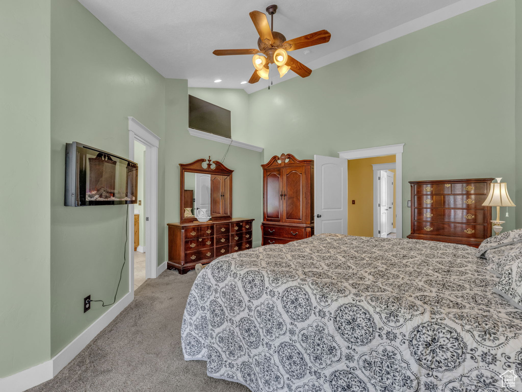 Carpeted bedroom featuring high vaulted ceiling, baseboards, and a ceiling fan