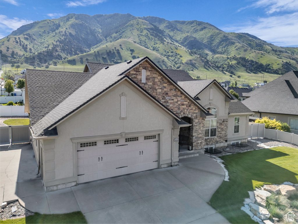 View of front of house featuring stucco siding, a shingled roof, a mountain view, and an attached garage