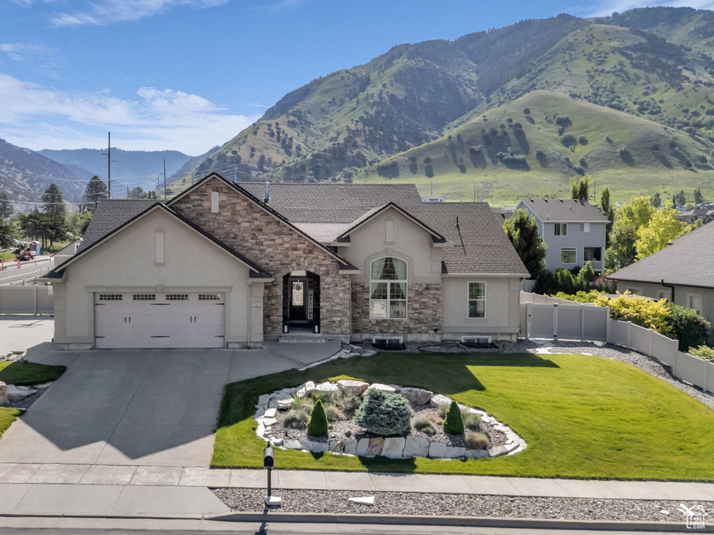 French country home featuring stucco siding, a garage, driveway, a mountain view, and stone siding
