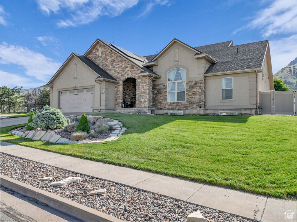 French provincial home with stucco siding, a gate, stone siding, a garage, and a shingled roof