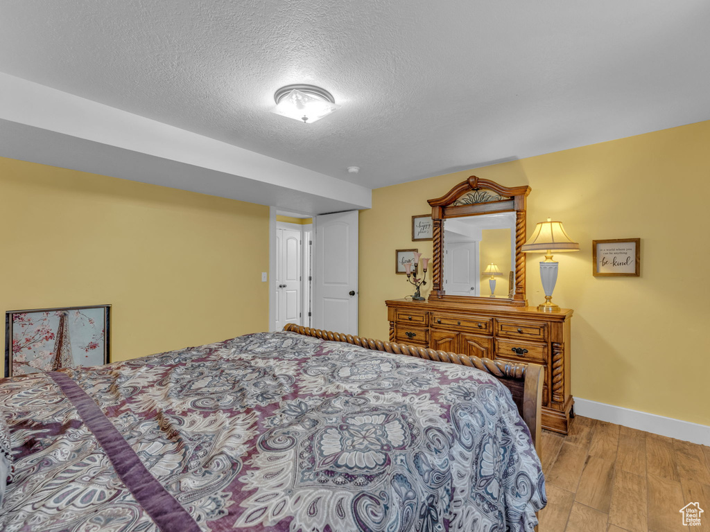 Bedroom featuring wood finished floors, baseboards, and a textured ceiling