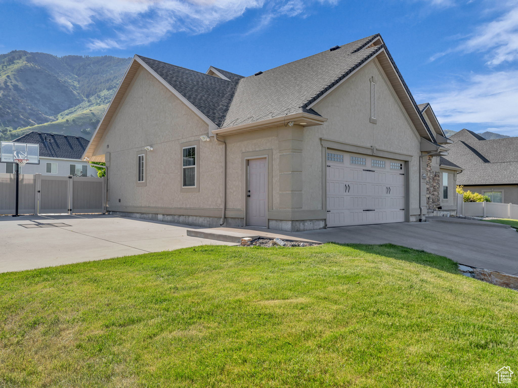 View of front of property featuring driveway, stucco siding, a mountain view, a gate, and an attached garage