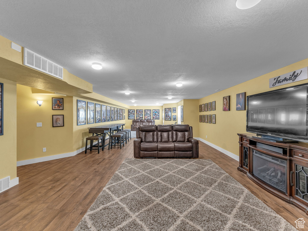 Living area featuring a textured ceiling, baseboards, and wood finished floors