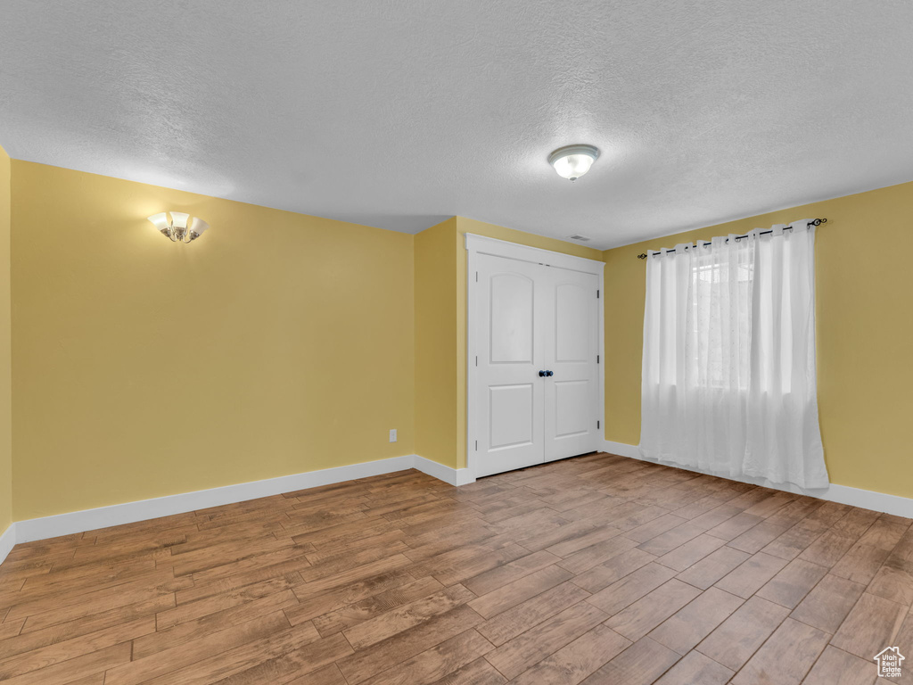 Spare room with a textured ceiling, baseboards, and wood finished floors