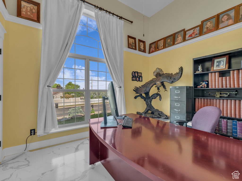 Office area featuring marble tiled flooring, plenty of natural light, a high ceiling, and baseboards