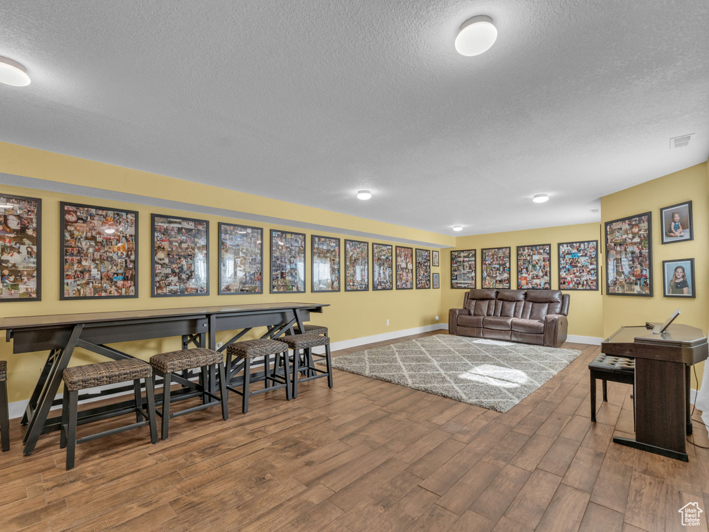 Dining space featuring a textured ceiling, baseboards, and wood finished floors