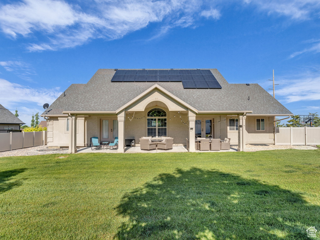 Back of house with outdoor lounge area, roof mounted solar panels, and a shingled roof