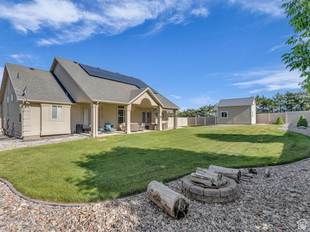 Back of property featuring an outdoor living space with a fire pit, roof mounted solar panels, roof with shingles, a patio, and stucco siding
