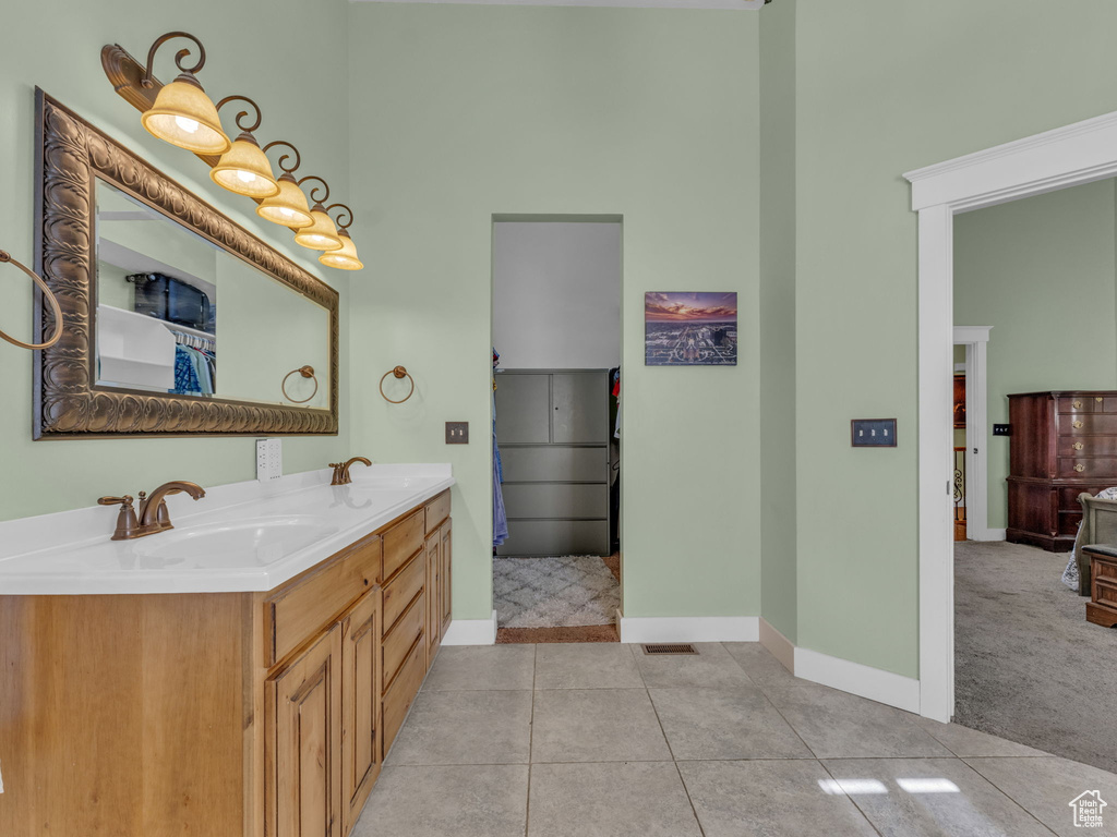 Full bathroom featuring a towering ceiling, double vanity, tile patterned flooring, and baseboards