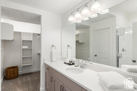 Bathroom featuring vanity, a stall shower, and baseboards