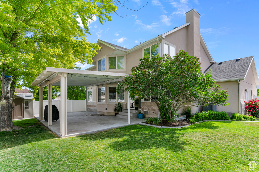 Rear view of property featuring stucco siding, a patio, and a lawn